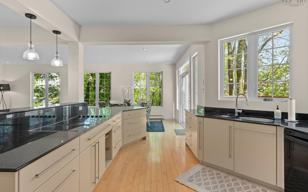 Kitchen featuring black dishwasher, a sink, light wood finished floors, recessed lighting, and dark stone counters