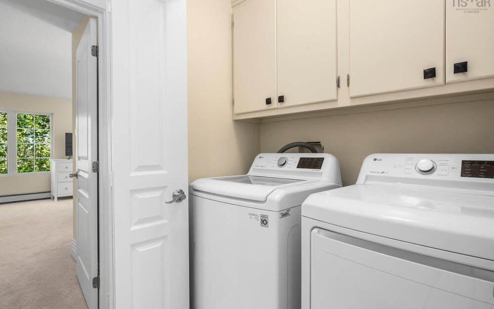 Laundry room featuring light carpet, washing machine and dryer, cabinet space, and a baseboard heating unit
