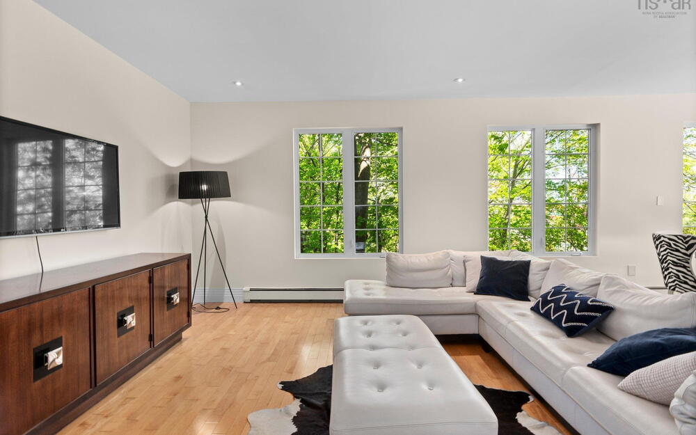 Living room featuring a baseboard heating unit, light wood-style flooring, healthy amount of natural light, and baseboards