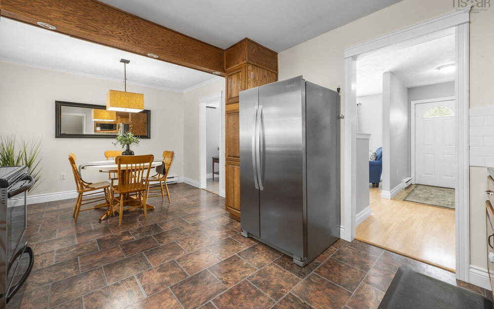 Kitchen space featuring tile-patterned flooring, wood-finish cabinetry, and a large stainless steel refrigerator