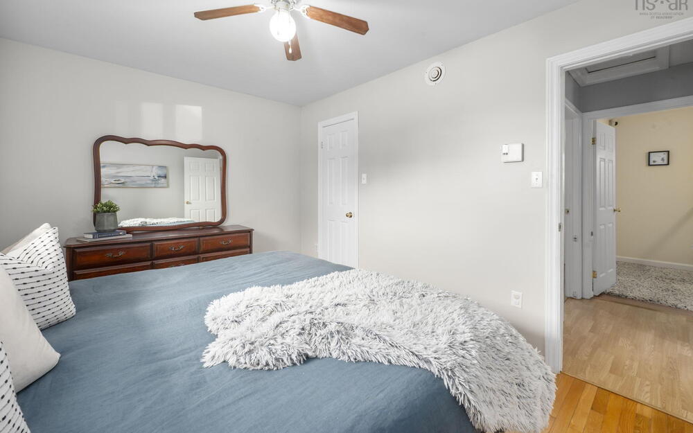 Bedroom featuring light neutral wall paint, wood-finish flooring, a ceiling fan with integrated lighting, and white paneled doors