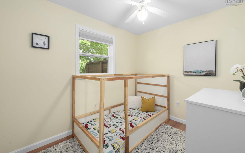 Room featuring wood-finish flooring, a ceiling fan with integrated lighting, and a white window frame with a blind