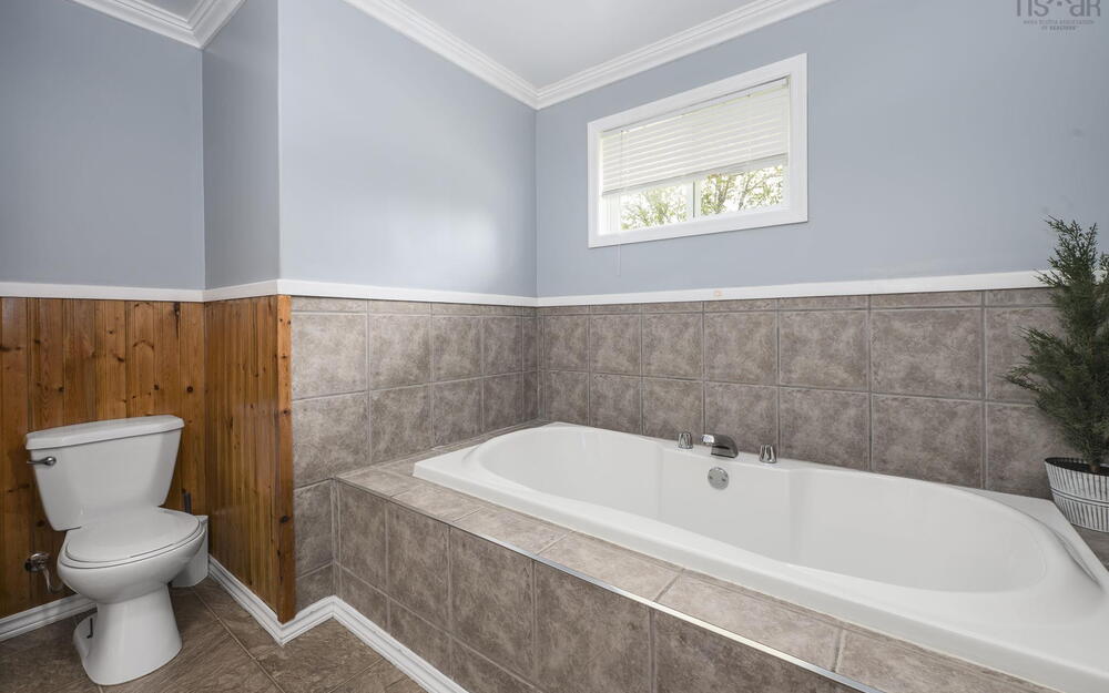 Built-in bathtub with chrome fixtures, surrounded by large format tile