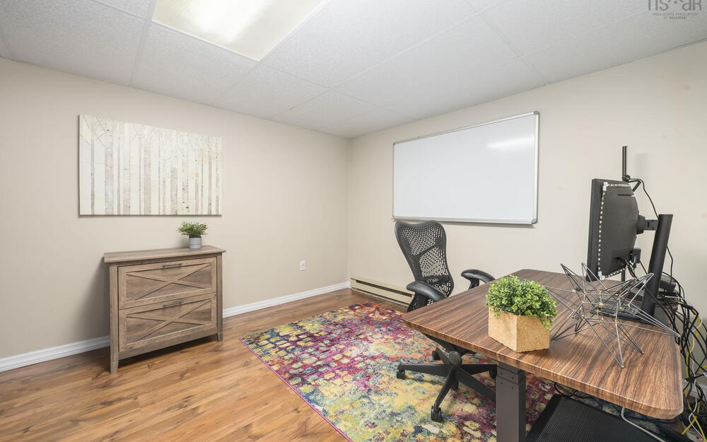 Interior room featuring wood-finish flooring, neutral wall paint, and a dropped ceiling with integrated lighting