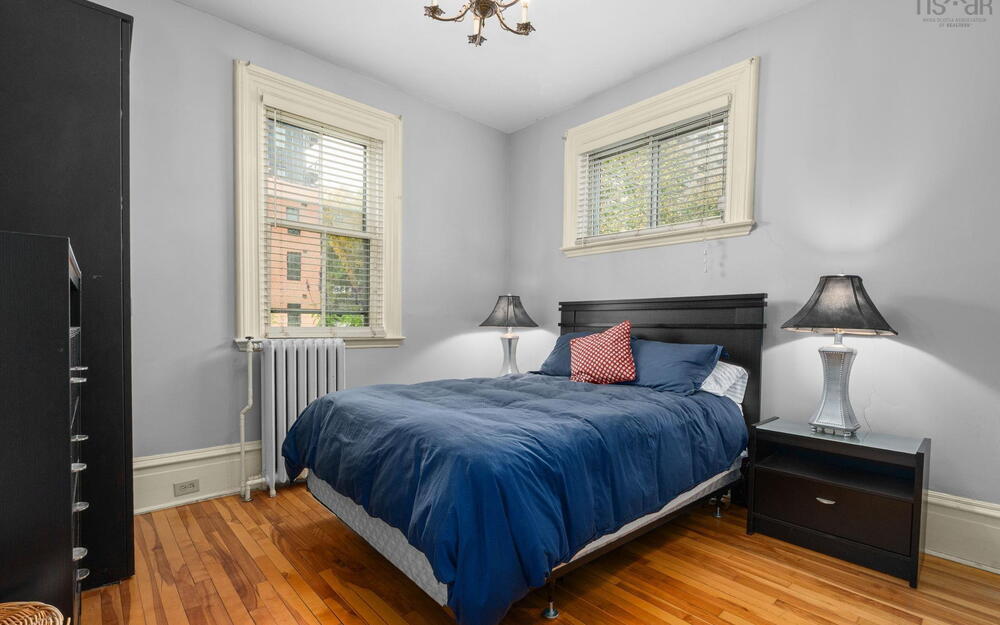 Room featuring hardwood flooring, multi-pane windows with detailed casing, a metal radiator, and a multi-arm chandelier