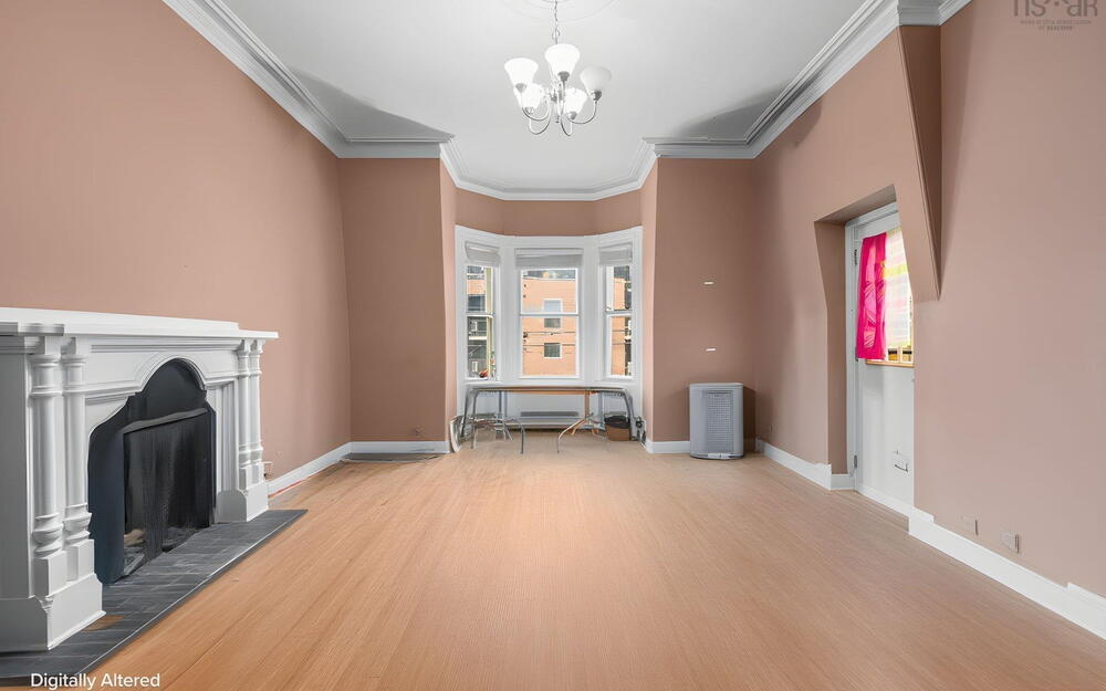 Interior featuring a classic fireplace mantel, bay windows, wood-finish flooring, ceiling crown molding, and a central ceiling light fixture