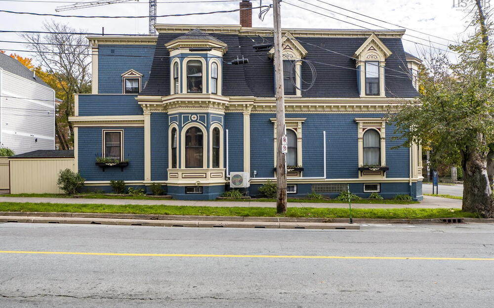 Second Empire exterior featuring a mansard roof, arched window detailing, decorative corbels, a three-story bay, and integrated window boxes