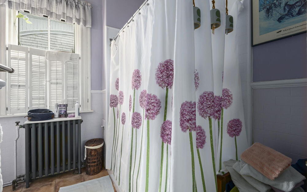Bathroom featuring white tile wainscoting, white wooden shutters, a multi-pane window, and a cast-iron radiator