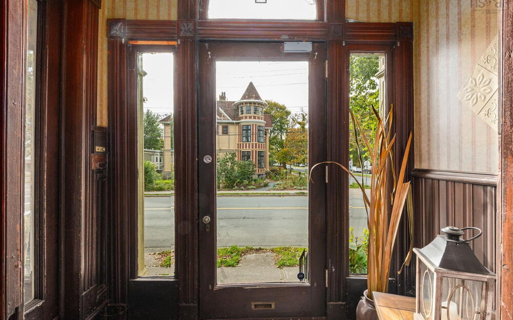 Entryway featuring a solid wood door with a glass pane, arched transom window, ornate wood trim molding, and vertical wainscoting