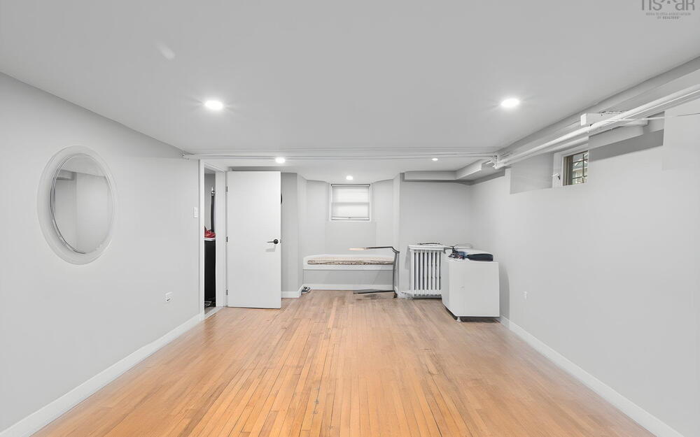 Interior space featuring wood-finish flooring, recessed lighting, a circular wall accent, and a window with a built-in bench