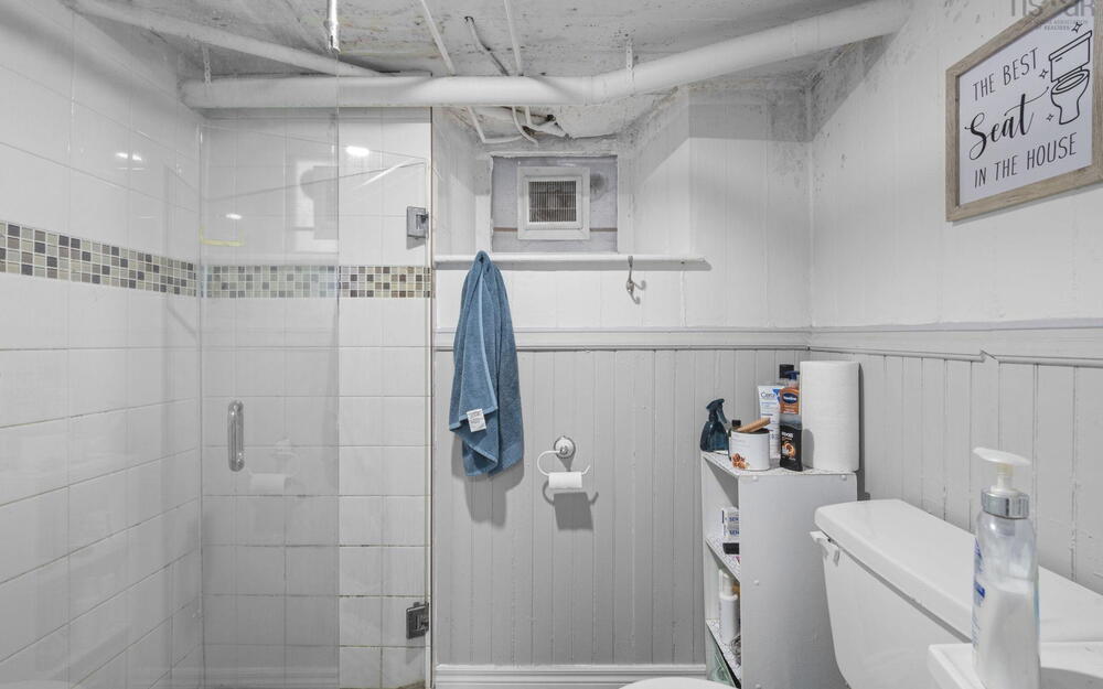 Shower enclosure featuring white wall tile with a glass tile accent border and a glass door, complemented by painted vertical wall paneling and a small window