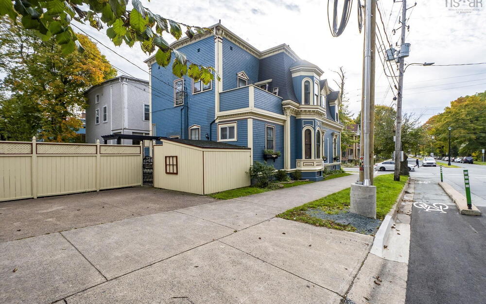 Victorian-style exterior featuring shingle siding, decorative trim, a mansard roof, arched window detailing, and a concrete driveway