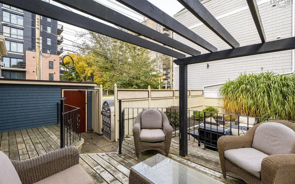 Outdoor wood deck featuring a black timber pergola, metal railing, and privacy fencing