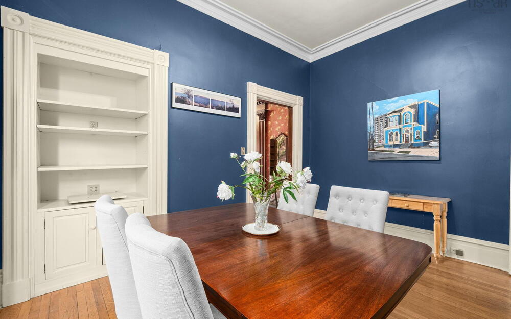 Built-in wall cabinetry with arched trim, original wood-finish flooring, and crown molding